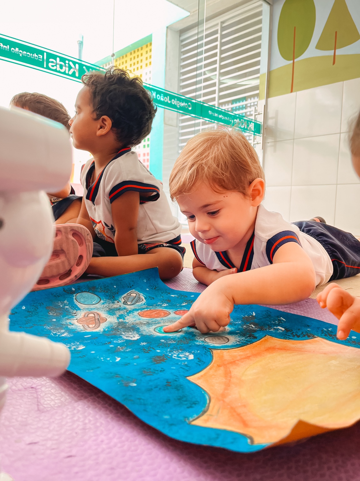 Crianças da Educação Infantil exploram uma atividade ilustrada com planetas