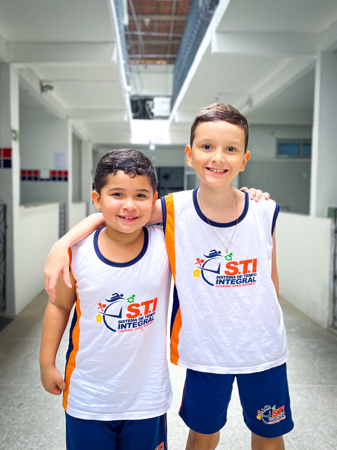Dois alunos com uniforme do STI abraçados no corredor do colégio