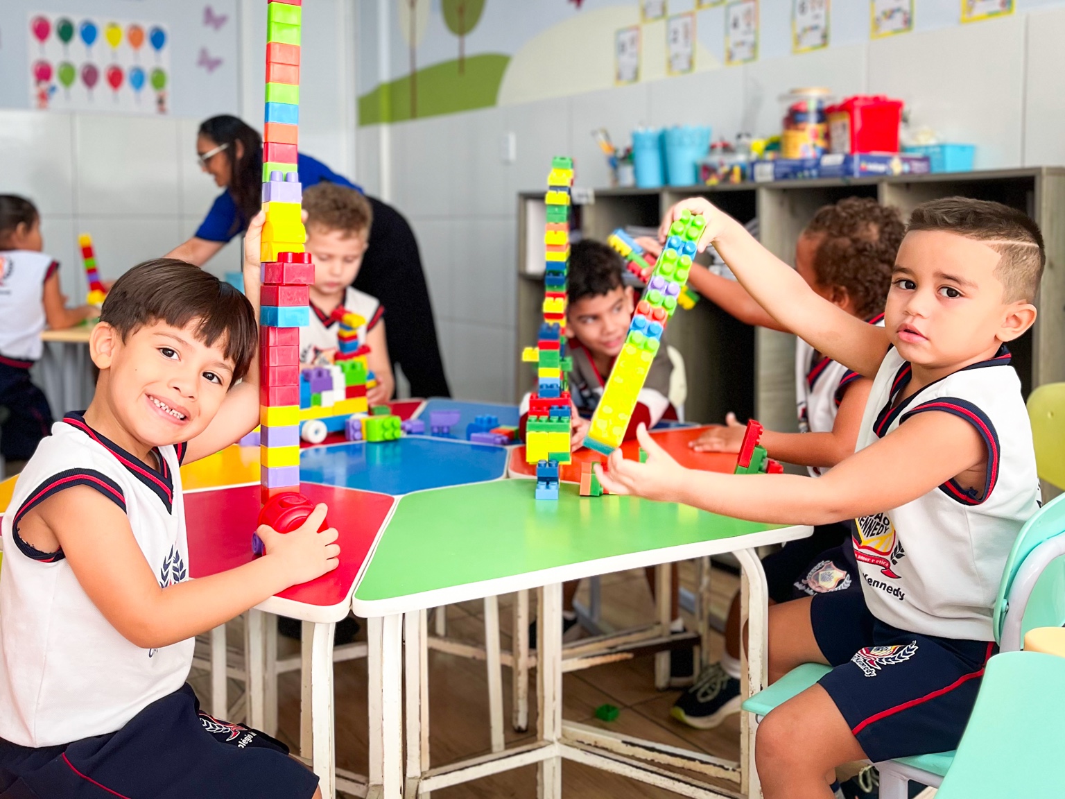 Crianças constroem torres com blocos coloridos na sala de aula