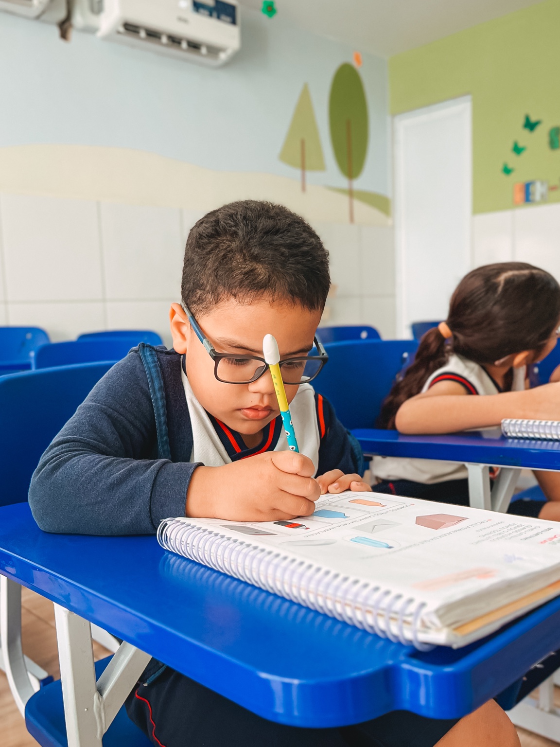 Aluno realiza uma atividade no livro em sua carteira