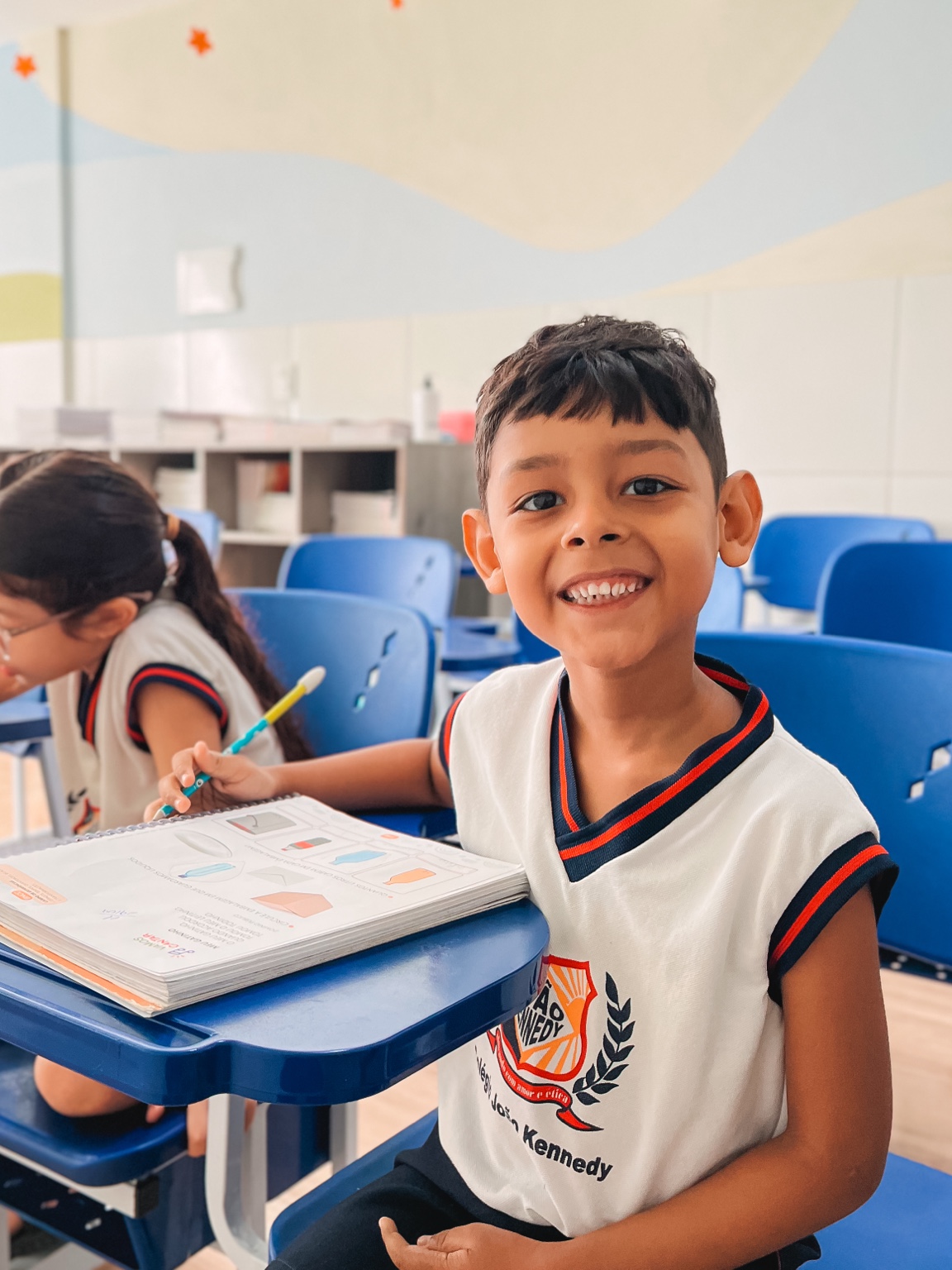 Aluno sorri durante uma atividade com o livro em sala de aula